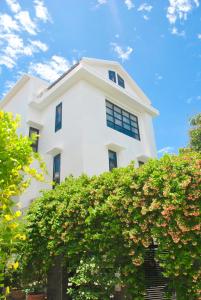 um edifício branco com um arbusto à frente em Hoi An Lotus Aroma Villa By HOS em Hoi An
