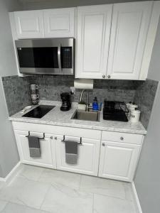 uma cozinha com armários brancos, um lavatório e um micro-ondas em Villa Sosa em Fort Myers