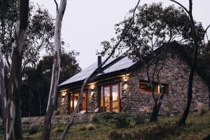 a stone house with lights on it in the woods at Mill Cabin —Luxury Granite Cabin, Mountain views in Crackenback