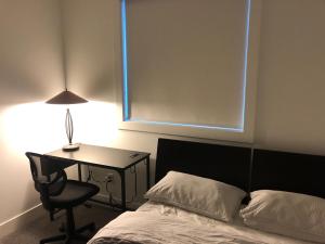 a bedroom with a bed and a desk with a lamp at Room in a New Guest House in Fort Saskatchewan