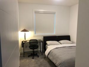 a bedroom with a bed and a desk and a window at Room in a New Guest House in Fort Saskatchewan