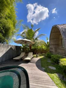 uma passarela de madeira com um guarda-sol e uma piscina em Tanhana Villa Canggu em Canggu