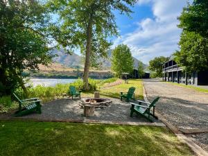 two green benches and a fire pit next to a lake at Steelhead Lodge in Lucile
