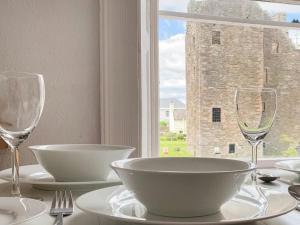 a table with bowls and wine glasses and a window at Cochrane House in Kirkcudbright