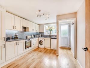 uma cozinha com armários brancos e piso em madeira em Wheelwrights Cottage em Yeaveley