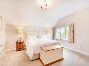 a white bedroom with a white bed and a window at Wheelwrights Cottage in Yeaveley