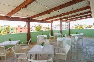 a patio with white tables and chairs and a green wall at Beautiful Three Storage House Near Playa Caleta in La Romana