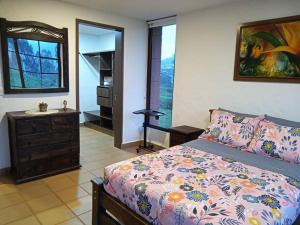 una camera da letto con un letto, un comò e uno specchio di Finca Mi Paraíso. Acogedora casa de campo a 5 minutos de Salento a Salento