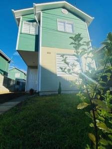 una casa verde y blanca con un patio de césped en Casa Aloe Villarrica con Aire Acondicionado en Villarrica