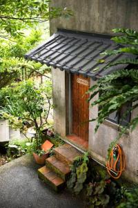 een klein huis met een houten deur en trap bij 濦崌四季 Lermite 金瓜石包棟民宿2-8人 in Ruifang