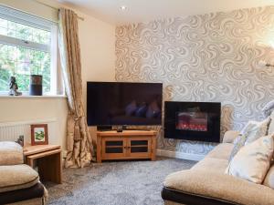 a living room with a flat screen tv on a wall at Lilly Lodge in Almondbury