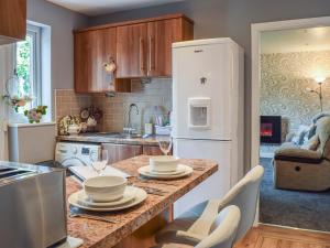 a kitchen with a table with glasses and a refrigerator at Lilly Lodge in Almondbury