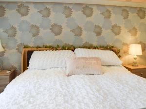 a bedroom with a white bed with a pillow on it at Lilly Lodge in Almondbury
