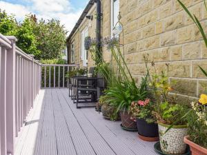 una terraza de madera con plantas y un banco en una casa en Lilly Lodge en Almondbury