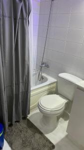 y baño con aseo y bañera con cortina de ducha. en Jardines en Santiago