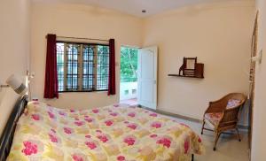 a bedroom with a bed and a chair and a window at Raintree Garden in Mysore