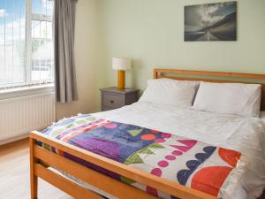 a bedroom with a bed with a colorful quilt on it at Gwynfa in Rhyl