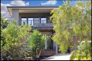 a house with a balcony and trees in front of it at Coastal Tones in Cowes