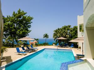 una piscina con sillas y sombrillas y el océano en High Life Resort & Spa, en Struie