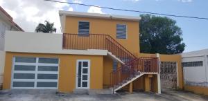 a yellow house with a staircase in front of it at Home San Juan in San Juan