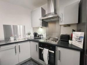 cocina con armarios blancos y fogones en Cityfront Modern Apt Near City Centre/Etihad, Free Parking en Mánchester