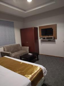 Habitación de hotel con cama, sofá y TV en فندق اضواء المدينة, en Sīdī Ḩamzah