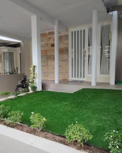 einen Garten mit künstlichem Gras in einem Haus in der Unterkunft Latasari 33A Homestay in Tuban