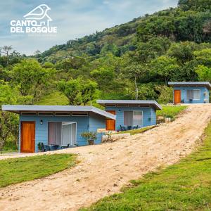 a couple of blue houses on a dirt road at Canto Del Bosque in San Vito