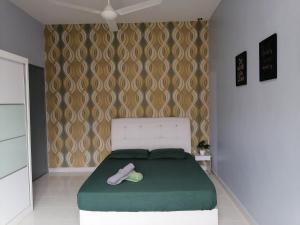a bedroom with a large bed with a green blanket at DKAMAR Homestay At Desaru, Fully Aircond, WiFi, Coway, Street View 4 min to Desaru Beach in Kangkar Chemaran