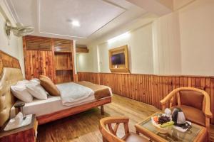 a bedroom with a bed and a table in a room at Goroomgo i Bex Manali Near Mall Road- Best Choice of Travellers in Manāli