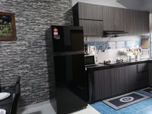 a black refrigerator in a kitchen with a brick wall at DKAMAR Homestay At Desaru, Fully Aircond, WiFi, Coway, Street View 4 min to Desaru Beach in Kangkar Chemaran