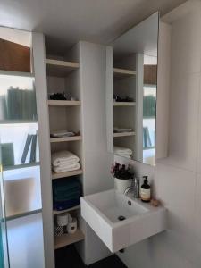 a white bathroom with a sink and a mirror at GREEN ROSE ~ Peaceful • Green • Haven in Canberra