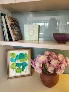 a shelf with a picture and a vase with flowers on it at GREEN ROSE ~ Peaceful • Green • Haven in Canberra
