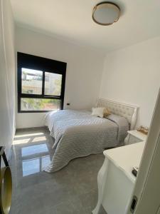 biała sypialnia z łóżkiem i oknem w obiekcie best apartment in buhcman (shivtie Israel 26) w mieście Modi'in