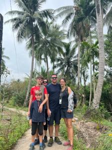 une famille posant une photo sur un chemin planté de palmiers dans l'établissement Mecong Homestay, à Ben Tre