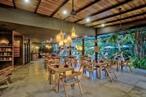 a restaurant with wooden tables and chairs and windows at Namu Garden Hotel & Spa in Puerto Viejo