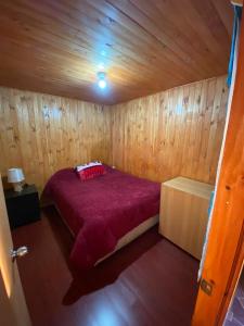 um quarto com uma cama num chalé de madeira em Hospedaje Pudahuel em Santiago