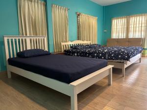 2 camas en una habitación con paredes azules en ThaiTae GuestHouse HuaHin, en Hua Hin