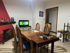 a dining room with a wooden table and a television at Casa Kime in Tortuguitas