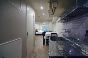 a kitchen with a sink and a couch in a room at KANDA HOUSE!! Shin-Okubo Walkable Modern Stay with Shinjuku Access in Tokyo