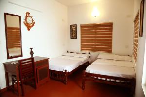 a room with two beds and a desk and a mirror at Back Packers Cochin Villa in Cochin