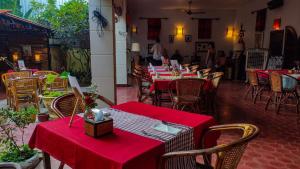 un restaurante con mesas y sillas con mantel rojo en Au Cabaret Vert en Battambang
