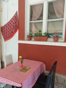 uma mesa com uma toalha de mesa xadrez vermelha e branca e uma janela em Etno Konak Angela em Kalna
