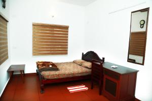 a bedroom with a desk and a bed and a table at Back Packers Cochin Villa in Cochin