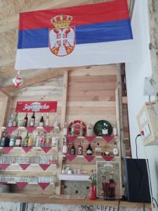 uma bandeira pendurada sobre um bar com garrafas de álcool em Etno Konak Angela em Kalna