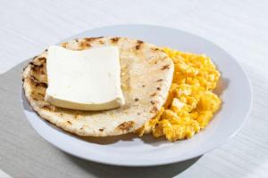 a white plate of food with eggs and a tortilla at Hostal Paraiso in Isla Mucura