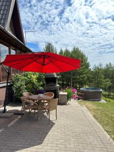 a table and chairs under a red umbrella on a patio at Sodyba Vilagio in Alanta