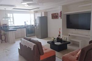 ein Wohnzimmer mit einem großen TV und einer Küche in der Unterkunft la casa hermosa in Quito