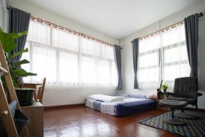 a bedroom with a bed and a chair and windows at Mystay Hostel Nan in Nan