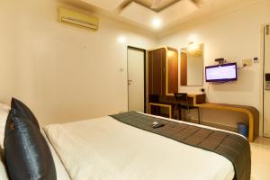 a hotel room with a bed and a television at Hotel Anand Heritage in Shirdi